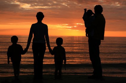 Young family watching sunset over the ocean